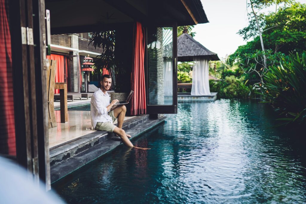 Skilled male freelancer with modern laptop technology posing at Indonesian courtyard