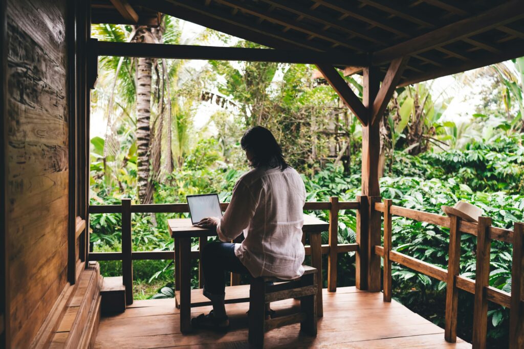 Unrecognizable freelancer working on laptop at table on veranda